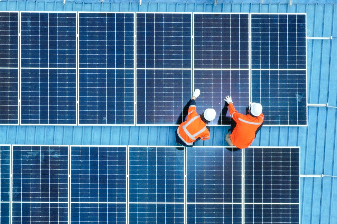 Photo despicts Male engineer installing photovoltaic solar panel system, Electrician or worker mounting solar module technology on roof of power industrial factory, alternative, renewable, sustainable energy. Top. view